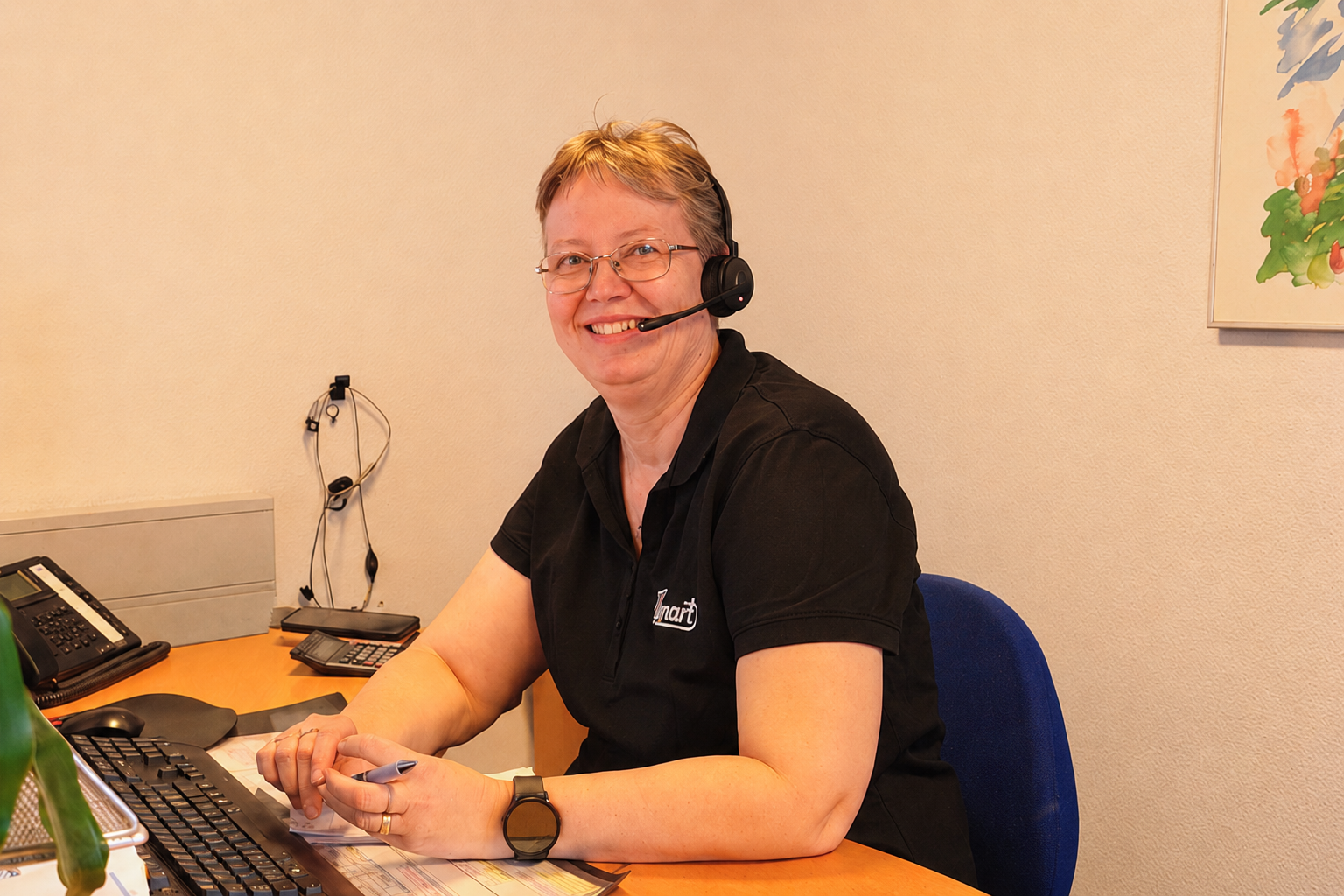 Medarbejder fra Repart kundeservice med headset ved skrivebord